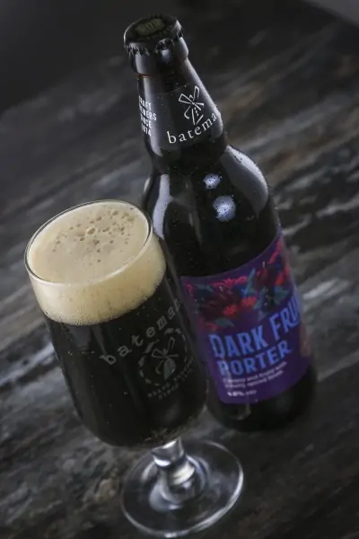 Bottle of Batemans Dark Fruit Porter poured into a pint glass say on a table